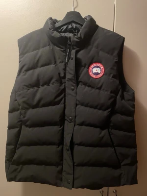 Svart dunväst från Canada Goose XL - Svart dunväst från Canada Goose i storlek XL. Västen är två år gammal men har inte använts mycket. köpt på johnells nypris 6999. skönt pris vid snabb affär