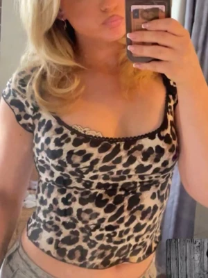 Leopardmönstrad croppad topp - Säljer en croppad topp med leopardmönster och korta ärmar. Toppen har en fyrkantig ringning med svart spetskant och är tillverkad i ett tunt, stretchigt material. Perfekt för dig som vill sticka ut med ett djurmönster och gillar trendiga detaljer. Från Nelly, första och sista bilen är på tröjan jag säljer, mitten bilden är lånad från nellys sida 💞