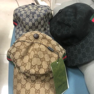 Gucci keps med GG-mönster och ränder - Säljer snygga Gucci kepsar med klassiskt GG-monogram i olika färger. Kepsarna har böjd skärm, justerbar rem bak och ikoniska gröna/röda ränder på sidorna. Finns i beige/brun, blå/grå och svart, alla i slitstark bomullscanvas med exklusiv känsla.. skriv för pris 