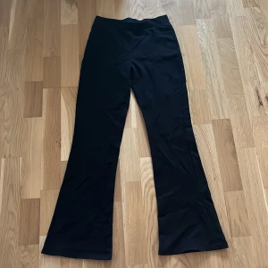 Svarta bootcut byxor med hög midja - Snygga svarta byxor med bootcut-snitt och hög midja. De har en slät och enkel design utan synliga detaljer eller fickor, vilket ger en clean look. Materialet känns mjukt och stretchigt, perfekt för dig som gillar bekväma och stilrena byxor. Har knappt använt och har bra skick. Säljer dem för att jag har växt ur dem.