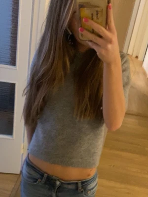 Grå stickad croppad topp från Zara - Säljer denna kortärmade stickade toppen från Zara. Modellen är lite croppad (på mig har kanten gått ungefär vid naveln) och är ribbad vid ärmslut och nederkant. Säljer då den blivit för liten för mig. Storleken är M men jag tycker att den är liten i storlek så skulle säga att den lutar mer åt S. (Tröjan kliar/sticks inte alls!)🌸