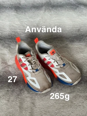 Adidas sneakers  - Säljer ett par snygga Adidas sneakers i mesh med röda och blå detaljer samt vita inslag. Skorna har klassiska Adidas-ränder på sidan, snörning och en sportig look. Perfekt för dig som gillar färgstarka och bekväma sneakers.🌸 Använt skick. Ej tvättade. Storlek 27 