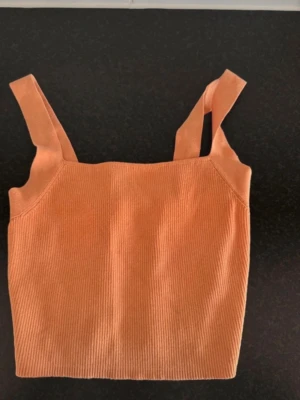 Ribbad orange linnetopp från Zara - Säljer en ribbad orange linnetopp från Zara i storlek S. Toppen har breda axelband och är croppad, perfekt för varma dagar. Materialet är mjukt och stretchigt, vilket gör den riktigt bekväm att bära.