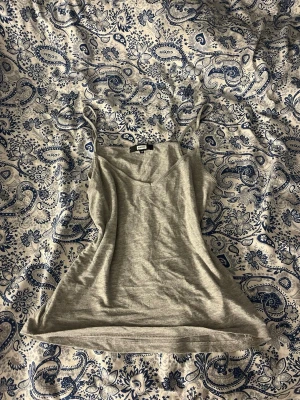 Grå linnetopp från Bik Bok - Säljer en enkel och stilren grå linnetopp från Bik Bok i storlek XS. Toppen har tunna axelband och en lätt v-ringad halsringning. Perfekt att matcha med jeans eller kjol för en avslappnad look.