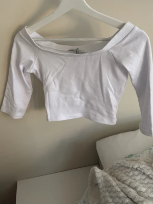 Vit offshoulder croppad topp  - Säljer en vit croppad topp från Zara med offshoulder-design och trekvartsärm. Aldrig använd. Toppen är ribbad och har en enkel, stilren look som passar perfekt till jeans eller kjol!