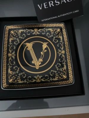 Versace tallrikar - Bilderna visar dekorativa tallrikar från Versace med gulddetaljer och klassiskt mönster. Kan användas för att lägga smycken, nycklar mm. Oanvända 