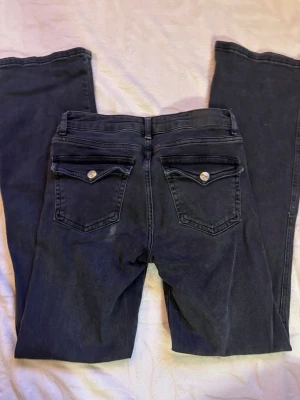 Svarta raka jeans från 157 - Säljer ett par svarta jeans från 157 som är bootcut . Jeansen har snygga bakfickor med lock och silverknappar. Smuts vid bakficka ( tror det går bort i tvätten)
