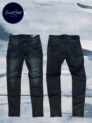 Replay Anbass grå jeans W30 L34 - Säljer ett par Replay Anbass jeans i grå tvätt med diskreta slitningar. Modellen har smal passform, klassisk femficksdesign och snygga detaljer vid fickorna. Tillverkade i stretchig bomullsblandning för extra komfort.