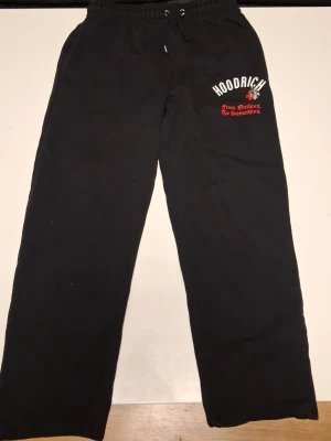 Svarta Hoodrich mjukisbyxor L - Svarta mjukisbyxor från Hoodrich med broderad logga och texten 'From Nothing To Something' i vitt och rött på vänster lår. Byxorna har resår och snörning i midjan samt raka ben. Perfekta för chill eller streetwear. Använd ett par gånger säljer för 199 Pris kan därmed absolut diksuteras. St på byxorna är då 10-12/L