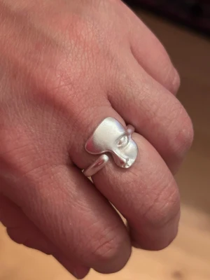 Ansikte ring  - Vacker ring i äkta sterling silver (925). Ringen har en stilren och unik form med mjuka, organiska linjer som ger ett modernt men tidlöst uttryck. Blank yta och bekväm passform. 