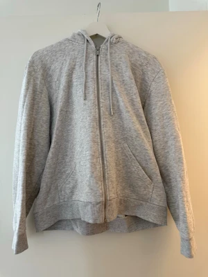 Grå hoodie med dragkedja och luva  - Säljer en mysig grå hoodie med dragkedja och luva. En perfekt tröja att mysa i hemma storlek L, känns som M-L
