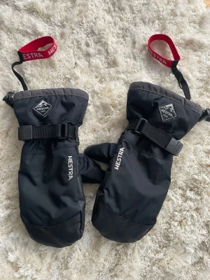 Hestra skidvantar - Säljer ett par jättefina och speciellt varma skidhanskar från Hestra!! De är i storlek 5 och är i jätte bra skick, de är i svart/mörkgrå design som passar till alla skidoutfits.  Nypris 650kr, Säljer pga de inte passar längre. De är i barn storlek men passar på mig som har färdig vuxna händer! 