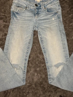 Ljusblå jeans från Gina Tricot, strl 152 - Säljer ett par ljusblå jeans från Gina Tricot i storlek 152. Jeansen har slitningar vid knäna, klassiska fem fickor och knappdetalj på bakfickan. De är sydda och lappade vid fickorna och vid ena hålet men inget man ser💕