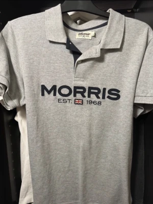 Grå pikétröja från Morris - Säljer en klassisk grå pikétröja från Morris med mörkblå broderad logga. Skicket är riktigt bra. Riktigt stilig och fin. Storlek M. Hör av er för  frågor. Mvh