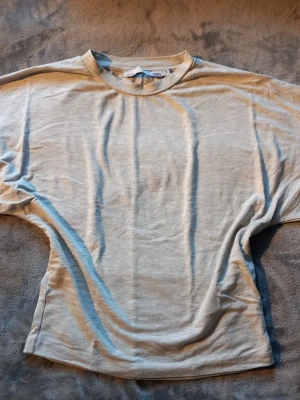 Ljusgrå t-shirt från 157, storlek S - En basic ljusgrå t-shirt från Lager 157 i storlek S. Modellen har rund hals och korta ärmar, tillverkad i mjuk bomull som känns skön mot huden. Perfekt för chill dagar och enkel att matcha med jeans eller shorts. Snyggt minimalistisk utan mönster eller detaljer.