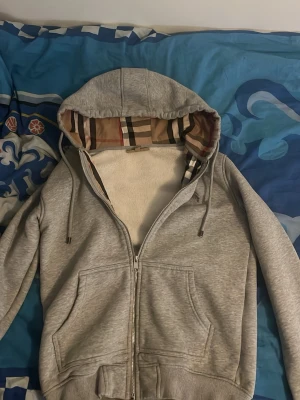 Grå burberry zip up hoodie - Grå Burberry zip up i mycket fint skick. Skön och bekväm passform, storlek S men passar även XS bra. Perfekt att använda året runt, funkar både som lager och ensam. Väldigt populär modell med stilren design. Självklart 100% äkta. Hör av dig vid frågor, om du vill ha frakt eller prissänkning!