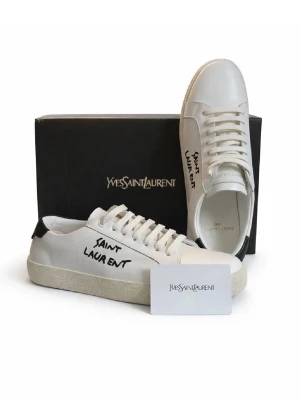 Saint Laurent sneakers  - Säljer ett par vita Saint Laurent sneakers olikfärgade med svart detal warning på hälen och handskriven logga på sidan. Skorna har klassisk snörning, platt sula och är tillverkade i slätt skinn. Perfekta för dig som gillar minimalistisk men edgy design.