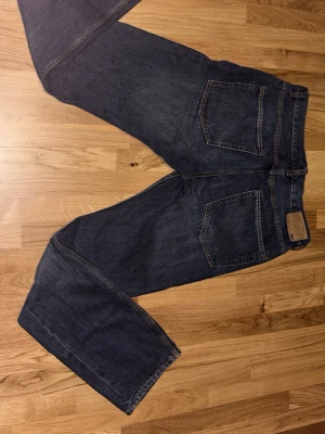 Lager 157 mörkblå jeans W31 L32 - Säljer ett par klassiska mörkblåa jeans. De har raka ben och snygga kontrastsömmar. Perfekta för dig som gillar tidlös denimstil och vill ha ett par jeans med riktigt bra passform.