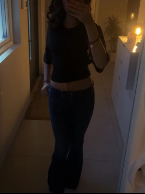 Mörkblå bootcut jeans med låg midja - Säljer ett par mörkblå jeans med bootcut-modell och låg midja. Jeansen har klassisk femficksdesign och är tillverkade i ett stretchigt denimtyg som sitter snyggt över höfterna och släpper ut vid benen. Perfekta för dig som gillar en retro vibe.