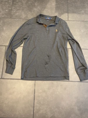 Grå pikétröja från Polo Ralph Lauren - Säljer en skit snygg polo raplh lauren tröja. Såklart äkta säljer den för den inte passar mig längre. Nypris :1499kr