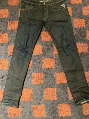Replay Anbass Mörkblå W32 - Säljer ett par mörkblå Replay Anbass jeans med skinny passform. Klassisk femficksmodell med Replay sömmar på bakfickan och detaljerade sömmar. Jeansen är tillverkade i stretchig denim för extra komfort och sitter tight hela vägen ner. Bilderna blev lite gula så jeansen är lite mer blåa i verkligheten