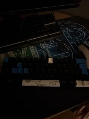 Deltaco Gaming DK430R - Deltaco Gaming DK430R mekaniskt tangentbord med unika keycaps och konstnärlig spacebar. Kompakt design, ansluts via USB. Tangenter i svart, blått och vitt. Synligt i gott skick utan tydliga defekter. Perfekt för gaming och skrivbordsbruk.