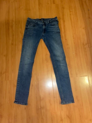 Replay jeans, storlek W31 L32 - Säljer ett par klassiska blå jeans från Replay i storlek W31 L32. Jeansen har en slim passform med raka ben, fem fickor och snygga slitningar framtill. Tillverkade i mjukt denimtyg som sitter skönt hela dagen.