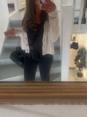 Beige kofta med knappar - Säljer en beige, croppad kofta med långa ärmar och snygga knappar framtill. Koftan är stickad och har en enkel, clean look som passar perfekt till jeans eller kjol. Perfekt för lager på lager under höst och vår.