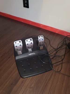 Logitech g29Racing Wheel Set med Pedaler och Växelspak - Komplett racing wheel set från Logitech med pedaler, växelspak och ratt. Perfekt för bilspel och racing-simulatorer. Ratten har specialdesignade gula handtag och Red Bull-dekal. Allt ser ut att vara i gott skick med mindre kosmetiskt slitage på ratten orginal ratten medföljer som ny 