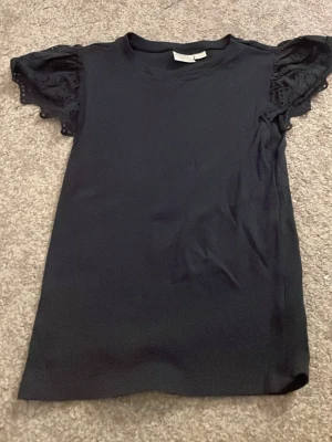 Svart topp med spetsärmar Gina Tricot - Säljer en svart topp från Gina Tricot i storlek 170. Toppen har korta, vågiga ärmar med broderad spetsdetalj som ger en söt touch. Rak passform och rund halsringning. Perfekt till jeans eller kjol!