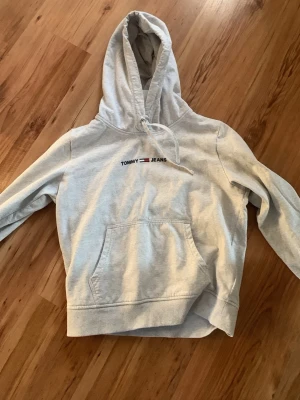 Grå Tommy Hilfiger hoodie - Grå Tommy Hilfiger hoodie i storlek XS. Tröjan är i mycket bra skick och är väldigt bekväm.