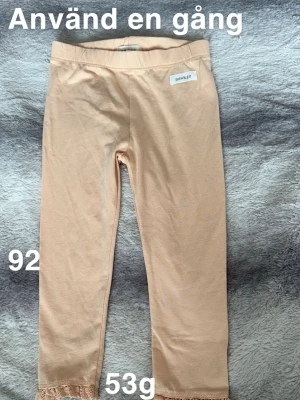 Aprikosfärgade leggings från Newbie med spets - Säljer ett par aprikosfärgade leggings från Newbie. Byxorna har elastisk midja och fina spetsdetaljer längst ner vid bensluten. Perfekta för en chill och söt look.🌸 Oanvända. Endast upptvättade. Storlek 92
