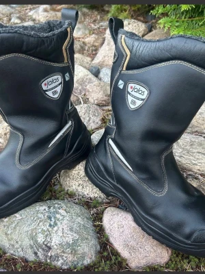 Jalas svarta vinterkängor i skinn - Hej och välkommen.   Du kollar på ett par riktigt varma och sköna skyddsstövlar av kvalitetsmäket Jalas i strl 41.   Stövlarna är endast provade på fot vid några enstaka tillfällen så är givetvis i mycket bra begagnat skick.  Nypris ca 2000:-   Rejäla skyddsstövlar som klarar av de mesta i de flesta väder året om.   Varmfodrad modell med extra bra dämpning och stöd.  Tåhätta och spikakydd finns.  