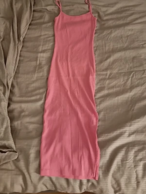 Rosa långklänning med smala axelband - Säljer en enkel och snygg rosa långklänning med smala axelband. Klänningen har en rak passform. Den har ett ribbat material.
