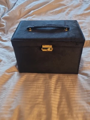 Svart smyckeskrin  - Det är ett svart smyckeskrin med två lådor och lite annat förvaring väldigt användbar. Den har gulliga detaljer och den är ganska så stor.