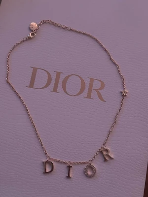 Dior guldhalsband  - Bilderna visar ett halsband från Dior i guld med bokstäverna D-I-O-R och en liten stjärndetalj, helt nytt 