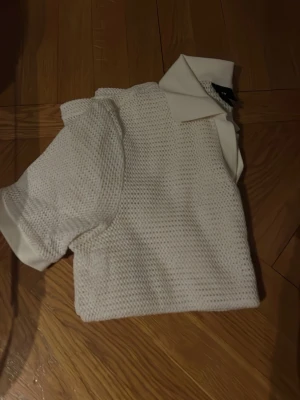 Vit stickad polotopp från H&M - Säljer en vit stickad polotopp från H&M i storlek S. Toppen har korta ärmar, klassisk krage och är tillverkad i ett luftigt stickat material som ger en snygg struktur. Perfekt för dig som gillar en clean och fräsch stil.