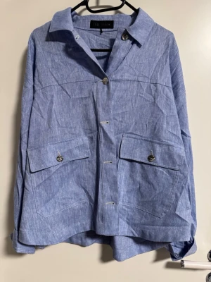 Blå linnekostym från Zara - Säljer en snygg blå kostym från Zara i linne. Kavajen har stora fickor med knappar och en avslappnad passform. Byxorna har hög midja, knappstängning och är lite avsmalnande nedtill. Perfekt för dig som gillar en chill men ändå stilren look.