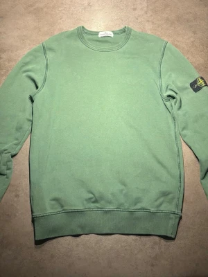 Stone Island Tröja - Säljer en riktig snygg och skön grön tröja från Stone Island. Storlek: Small/ Junior men är rätt så stor i storlek. Vid köp kommer dessutom en extra Stone Island Patch. Skriv vid frågor eller kom med bud!