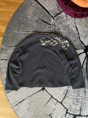 Derschutze Blossom Waffle Knit Tröja - Derschutze ”blossom” waffle knit-tröja i storlek L  Tillverkad i ett texturerat waffle knit-material med boxig, lätt croppad passform. Det subtila blomsterbroderiet ger plagget en tydlig identitet utan att kännas överdrivet. || Knappast använd.  || Märke: Derschutze || Modell: Blossom Waffle Knit Sweater || Färg: Mörkgrå / Charcoal || Material: Waffle knit (bomullsblandning) || Passform: Boxig / relaxed ||