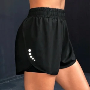 Svarta träningsshorts - Säljer ett par svarta träningsshorts från SHEIN i storlek S, har elastisk midja och reflekterande prickar på sidorna. Shortsen har en loose passform och dubbla walk-lager för extra komfort. Perfekta för gymmet och träning. Helt oanvända