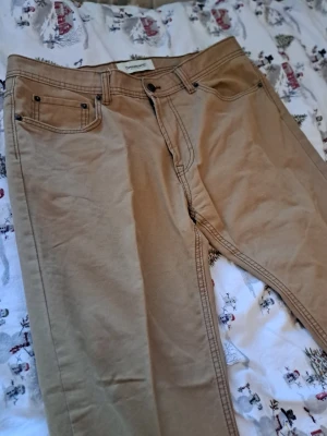Nya Dressman-byxor – storlk 38/30 – 100% bomull - Ett par jäyte fina helt nya och oanvända byxor från **Dressman**. Köpta men aldrig använda – i mycket fint skick.  **Detaljer:** * Storlek: **38/30** * Material: **100 % bomull** * Färg: beige/brun (se bilder) * Skick: **Nya / oanvända** Passar perfekt till både vardag och lite finare tillfällen.  Hör gärna av dig om du har frågor!  Lämnar självklart god omdömen om köparen gör det.  . Titta gärna på mina andra annonser!