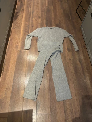 Grå ribbat stickat myssett från Cubus - Säljer en grå stickad tröja från C i storlek S tillsammans med ett par ribbstickade mjukisbyxor i XS. Tröjan och byxorna har ett ribbat mönster och tröjan har rund hals, samt långa ärmar. Perfekt för dig som gillar en enkel och chill stil. Materialet är mjukt och skönt stickat. Resåren i byxorna är vriden men går säkert att vrida tillbaka. de är i helt ok skick. 