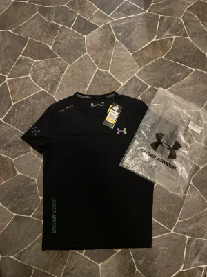 Under Armour Gym T-shirt  - En mycket fin T-shirt ifrån Under Armour med inga defekter. Plagget har aldrig använts pga ingen användning, därmed vill jag bara bli av med den.                                                                 Priset kan diskuteras!