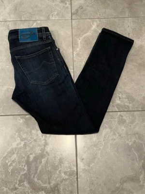 Jacob Cohën jeans - Snygga mörkblå jeans från Jacob Cohën. En blå patch på bakfickan och broderade detaljer vid gylfen, broderat J på fickan ger de en cool look. Perfekta för dig som gillar stilrena jeans med premiumkänsla. Storleken är i W29.