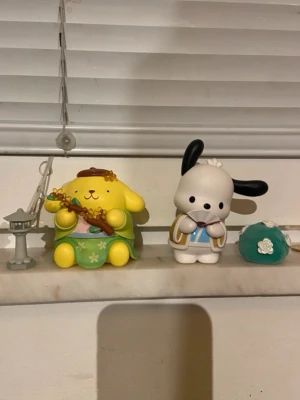 Sanrio figurer pompompurin och pochacco - Säljer en söt figur med små blommor från Sanrio, PomPomPurin och figuren pochacco