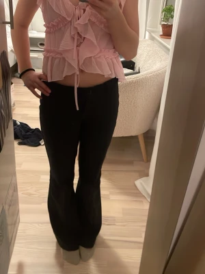 Rosa topp - Säljer en söt rosa blus från Amisu i storlek XS. Blusen har omlott-design, volanger och tunna axelband. Materialet är lätt och plisserat syntet, med knyt framtill och v-ringad hals. 