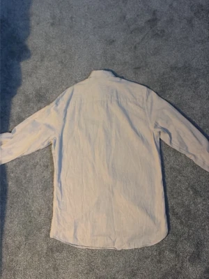 Beige linneskjorta från Oscar Jacobson - Snygg beige skjorta från Oscar Jacobson i storlek S, slim fit. Tillverkad i mjukt linne med klassisk krage och knappar hela vägen. Perfekt för dig som gillar stilrena och enkla plagg med skön passform.