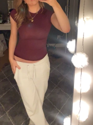 Mörkröd tight kortärmad topp - Säljer en mörkröd, tight och kortärmad topp med rund hals. Toppen har en enkel och stilren design utan mönster eller detaljer, perfekt att matcha med olika outfits. Materialet känns mjukt och följsamt mot kroppen. Passar dig som gillar en slim och figurnära look🤍