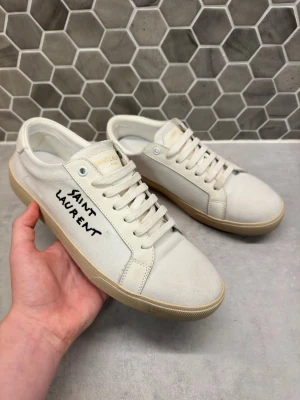 Saint Laurent vita  - Tjena! Säljer ni ett par fräscha vita skor från Saint Laurent|| med beige sula och svart saint laurent text på sidan|| skorna är i bra skicka, kunde inte hitta några större defekter|| Storlek 42 (passar även 43)|| hör av dig om du har några frågor🙌// StenhamCloset